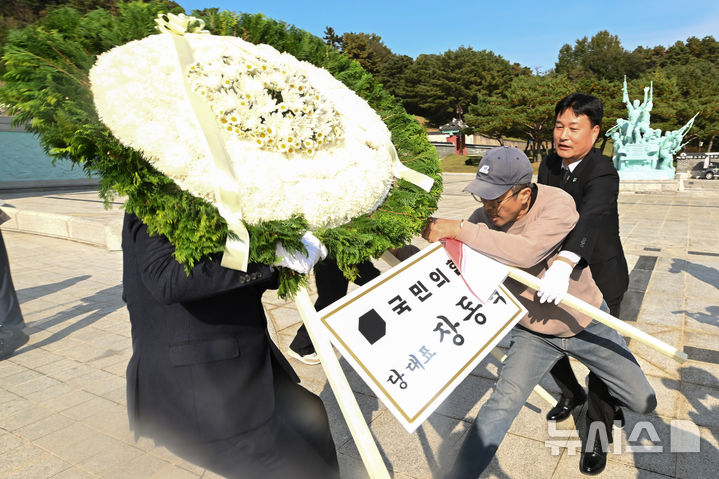 [광주=뉴시스] 이영주 기자 = 장동혁 국민의힘 당대표가 광주를 방문한 6일 광주 북구 운정동 국립5·18민주묘지에서 한 시민이 장 대표의 화환을 치우다 묘역 관계자들과 몸싸움을하고 있다. 2025.11.06. leeyj2578@newsis.com