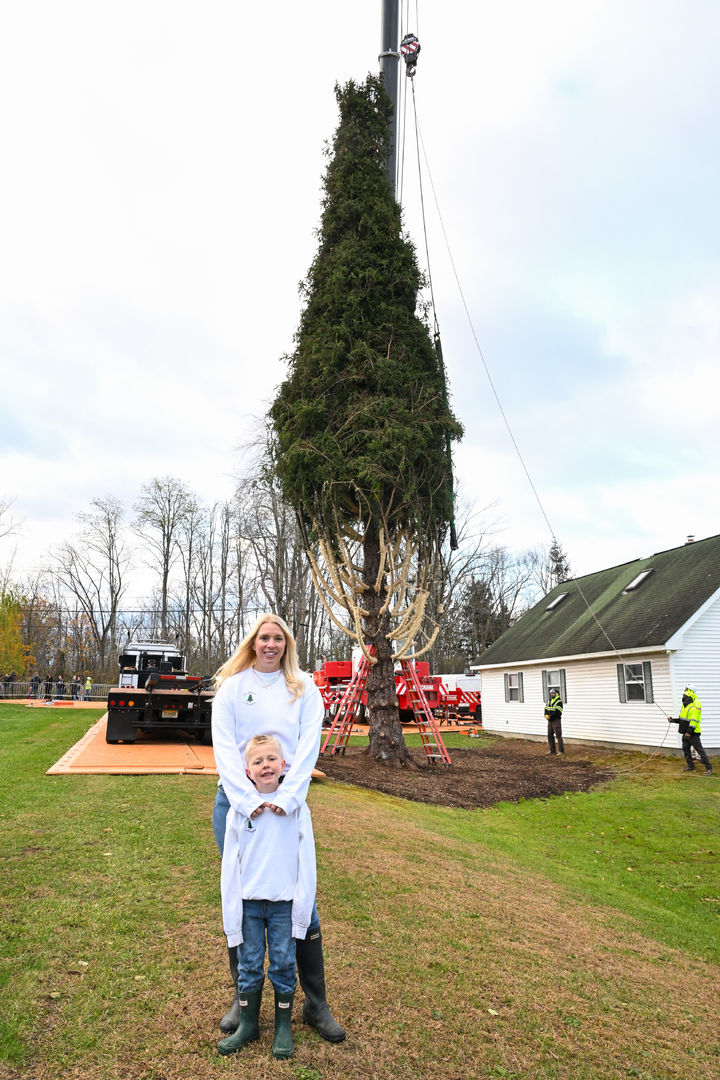[이스트 그린부시=AP/뉴시스] 6일(현지 시간) 미 뉴욕주 이스트 그린부시에서 주디 러스와 아들 리엄이 올해 록펠러센터 크리스마스트리로 기증한 높이 약 23m, 무게 11톤의 노르웨이 가문비나무 앞에서 마지막 기념 촬영을 하고 있다. 이 나무는 뉴욕시로 운반돼 8일 록펠러센터 앞에 세워질 예정이다. 2025.11.07.
