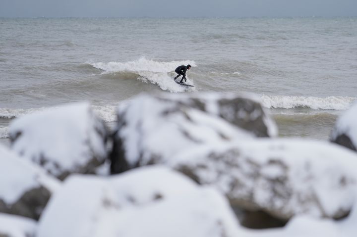 [시카고=AP/뉴시스] 눈이 내린 10일(현지 시간) 미국 일리노이주 시카고 교외 에반스턴 인근 해변에서 서퍼가 서핑을 하고 있다. 2025.11.11.