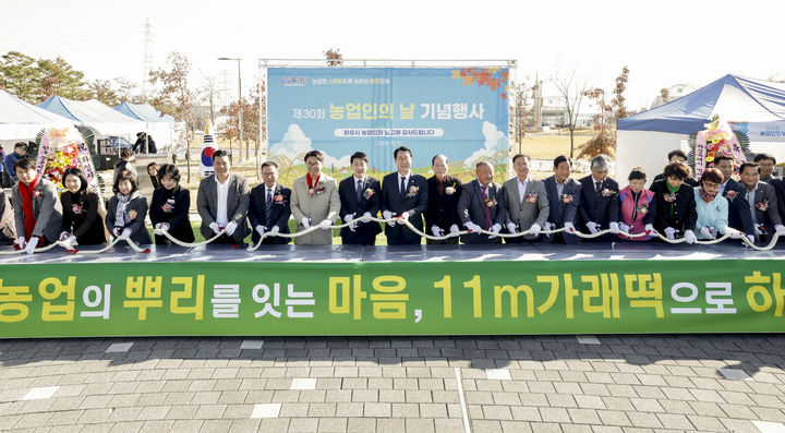 [화성=뉴시스]정명근 화성시장(사진 가운데)이 11일 주요 내빈들과 함께 제30회 농업인의 날 기념 테이프커팅을 대신해 11m 길이의 가래떡을 자르고 있다.(사진=화성시 제공)2025.11.11.photo@newsis.com *재판매 및 DB 금지