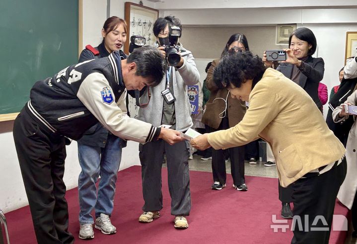 [서울=뉴시스] 한이재 기자 = 12일 오후 서울 마포구 일성여자중고등학교 지하 다목적실에서 김형빈 3학년 4반 담임이 최고령 수험생인 서혜숙(78)씨에게 수험표를 건네며 서로 인사하고 있다. 2025.11.12. nowone@newsis.com