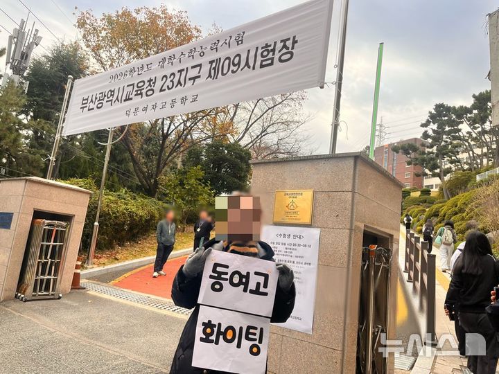 [부산=뉴시스] 진민현 기자 = 2026학년도 대학수학능력시험일인 13일 부산 수영구 덕문여자고등학교 앞에서 동여자고등학교 교사가 학생들을 응원하기 위해 '동여고 화이팅'이라는 응원 팻말을 들고 수험생들을 응원하고 있다. 2025.11.13 truth@newsis.com