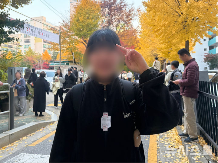 [서울=뉴시스] 전수현 인턴기자 = 13일 오후 서울 영등포구 여의도여자고등학교 앞에서 2026학년도 대학수학능력시험을 마친 정재은(19)씨가 사진 촬영을 위해 자세를 취하고 있다. 겉옷에는 책상에 붙어 있던 스티커가 붙어 있다. 2025.11.13. photo@newsis.com