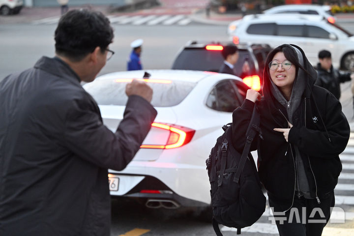 [광주=뉴시스] 이영주 기자 = 2026학년도 대학수학능력시험이 치러지는 13일 오전 광주 북구 광주시교육청 26지구 제28시험장(국제고등학교)에서 한 시민이 시험장으로 들어서는 수험생을 응원하고 있다. 2025.11.13. leeyj2578@newsis.com