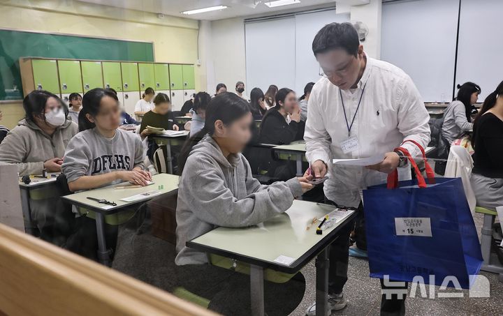 [서울=뉴시스] 사진공동취재단 = 2026학년도 대학수학능력시험(수능)이 실시된 13일 오전 서울 광진구 광남고등학교 고사장에서 수험생이 감독관에 휴대폰을 제출하고 있다. 2025.11.13. photo@newsis.com **기사 내용과 직접 관련 없습니다**