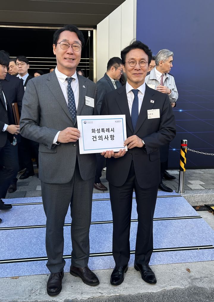 [화성=뉴시스]정명근 화성시장(사진 왼쪽)이 14일 우정읍 기아 오토랜드 화성에서 열린 '기아 목적기반모빌리티 전용 공장 준공 및 기공식'에서 김민석 국무총리에게 건의사항을 전달한 후 기념촬영을 하고 있다.(사진=화성시 제공)2025.11.14..photo@newsis.com *재판매 및 DB 금지