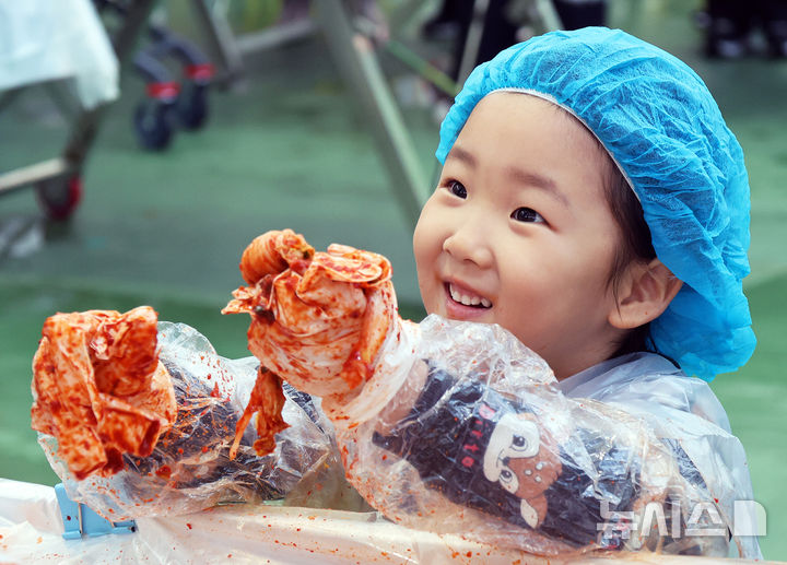 [평창=뉴시스] 14일 강원 평창군 진부면민체육공원에서 열리고 있는 '제8회 평창고랭지김장축제'에서 부모와 함께 축제장을 찾은 어린이가 김장체험을 하고 있다. (사진=평창군 제공) 2025.11.14. photo@newsis.com