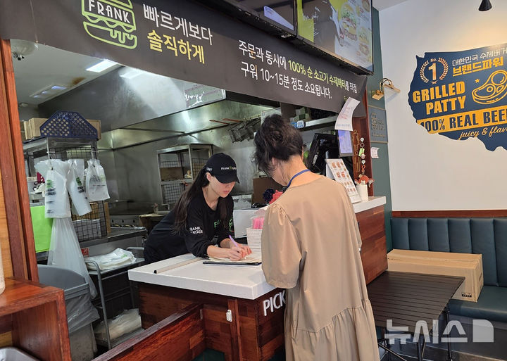 [성남=뉴시스]성남시 어린이 기호식품 전담관리원이 지난 9월 학교 주변 햄버거 판매점에서 영업자와 종업원의 건강진단 실시 여부를 점검하고 있다(사진=성남시 제공)2025.11.17.photo@newsis.com