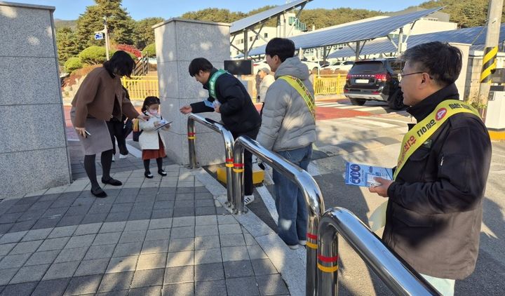 [평창=뉴시스] 등교하는 초등생과 보호자에게 안전 수칙이 담긴 홍보물 배부하는 모습. (사진=평창군 제공) 2025.11.17. photo@newsis.com *재판매 및 DB 금지