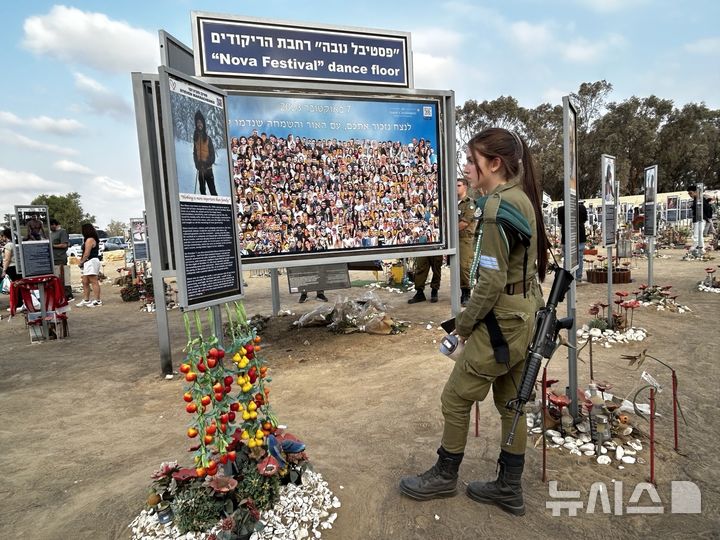 [이스라엘 레임=뉴시스] 최명수 기자 = 2023년 10월7일 새벽 팔레스타인 무장정파 하마스가 기습 공격을 단행한 이스라엘 레임지역 노바페스티벌 현장에 세워진 추모 시설. 이스라엘방위군(IDF) 소속 여군이 희생자 사진을 보고 있다. 2025.11.11. apollon@newsis.com 