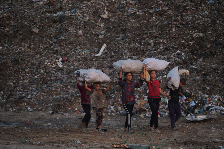 [자와이다=AP/뉴시스] 18일(현지 시간) 가자지구 중부 자와이다 매립지에서 팔레스타인 어린이들이 나무와 플라스틱, 캔 등을 주워 담은 자루를 머리에 이고 돌아가고 있다. 2025.11.19.