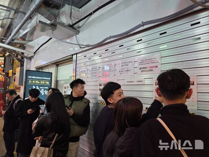 [서울=뉴시스][서울=뉴시스]김윤영 수습기자=26일 오후 12시께 찾은 서울 종로구 광장시장 내 외국인 관광객들이 좁은 통로에서 음식을 먹고 있다. 2025.11.26 photo@newsis.com