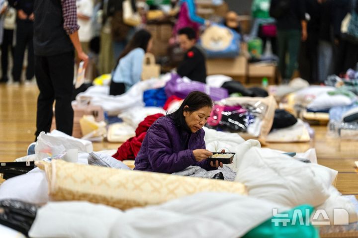 Resident rests at a temporary shelter near the fire scene at Wang Fuk Court, a residential estate in the Tai Po district of Hong Kong's New Territories, Thursday, Nov. 27, 2025. (AP Photo/Chan Long Hei)