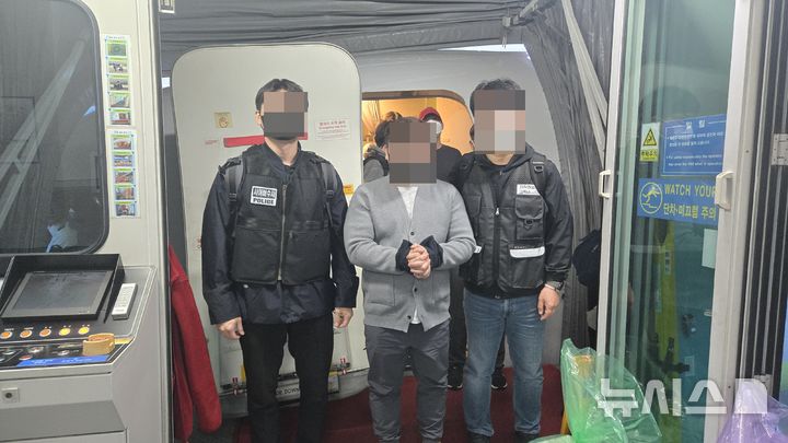 [서울=뉴시스]경찰청은 국내외 영화, 드라마, 웹소설 등을 불법으로 게시한 총책 40대 남성 A씨와 캄보디아 거점 로맨스 스캠(연애 빙자 사기) 조직원으로 활동한 30대 남성 B씨를 이날 오전 인천국제공항을 통해 강제송환했다고 밝혔다. 사진은 피의자 A씨(가운데)가 인천국제공항 도착 게이트에서 송환되고 있는 모습. (사진=경찰청 제공)