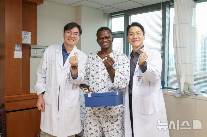 [서울=뉴시스] 서울아산병원에서 대퇴골 재건 및 피부 이식 수술을 받은 존 콘테(가운데)씨가 13일 의료진과 기념사진을 찍고 있다. 왼쪽이 김지완 정형외과 교수, 오른쪽이 권진근 성형외과 교수. (사진= 서울아산병원 제공)