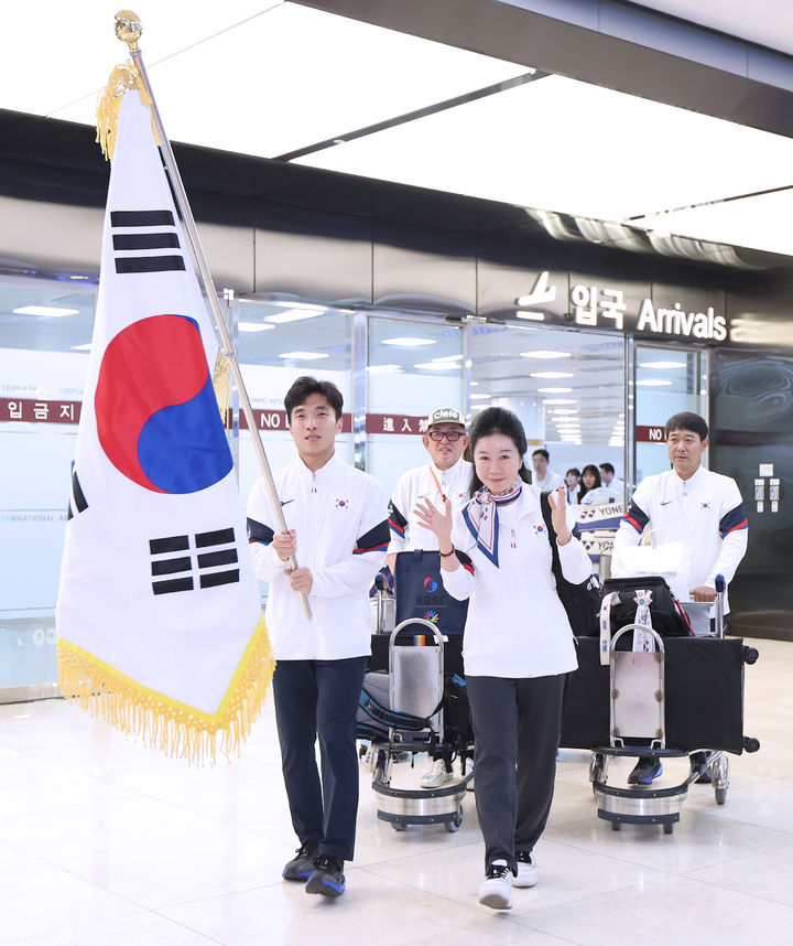 [서울=뉴시스]2025 도쿄 데플림픽 대한민국 선수단을 대표하여 문경화 선수단장(오른쪽)과 배드민턴 신경덕 선수(왼쪽)가 단기를 들고 입국하고 있다. (사진=대한장애인체육회 제공)