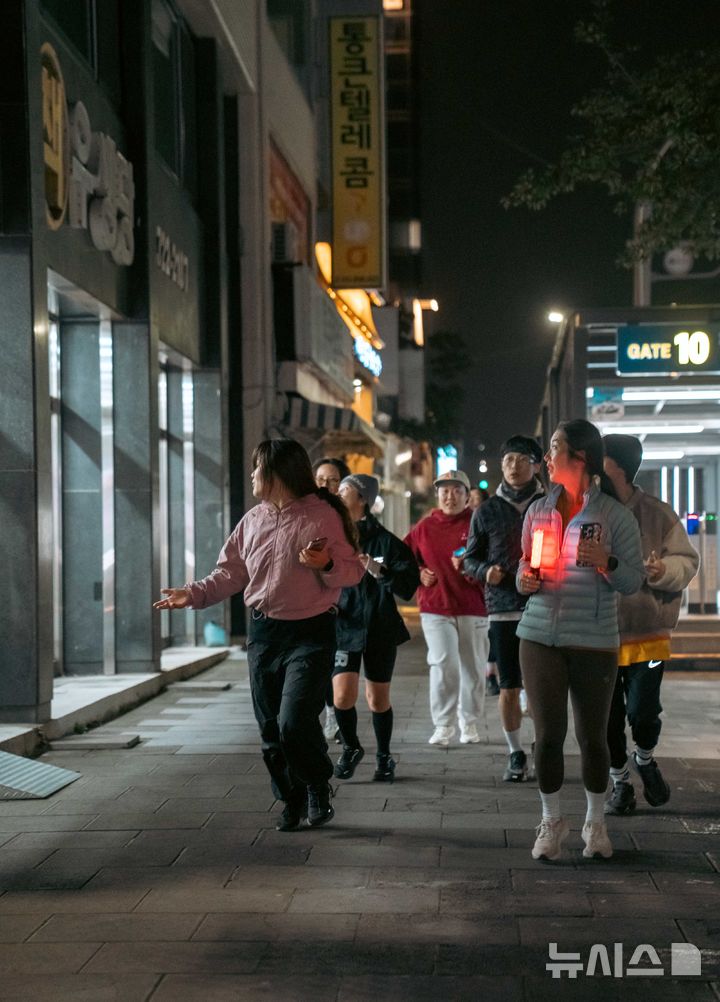 [제주=뉴시스] 27일 오후 '원도심 시티런'에 참여한 러너들이 로컬 큐레이터와 함께 달리며 골목 곳곳의 작은 가게들을 살펴보고 있다. (사진=구보 제공) 2025.11.28. photo@newsis.com