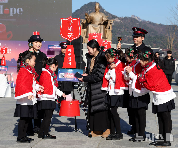 [서울=뉴시스] 추상철 기자 = 28일 오전 서울 종로구 광화문광장에서 열린 '2025 구세군 자선냄비 시종식'에서 서울 주니어 합창단 어린이와 학부모가 현금 및 NFC 자선냄비 모금 시연을 하고 있다. 2025.11.28. scchoo@newsis.com