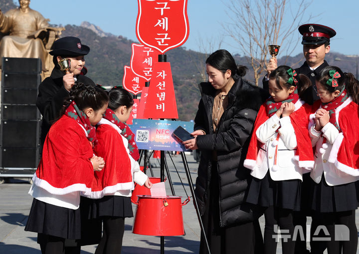 [서울=뉴시스] 추상철 기자 = 28일 오전 서울 종로구 광화문광장에서 열린 '2025 구세군 자선냄비 시종식'에서 서울 주니어 합창단 어린이와 학부모가 현금 및 NFC 자선냄비 모금 시연을 하고 있다. 2025.11.28. scchoo@newsis.com