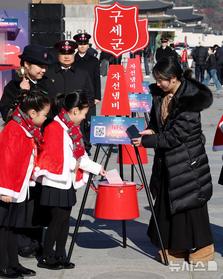 [서울=뉴시스] 추상철 기자 = 28일 오전 서울 종로구 광화문광장에서 열린 '2025 구세군 자선냄비 시종식'에서 서울 주니어 합창단 어린이와 학부모가 현금 및 NFC 자선냄비 모금 시연을 하고 있다. 2025.11.28. scchoo@newsis.com