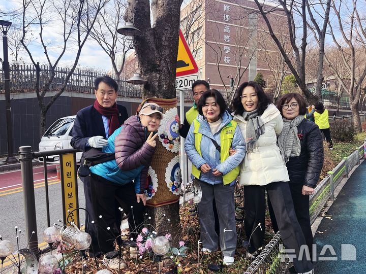 [군포=뉴시스] 군포시, 수리동 주민자치회가 최근 관내 수릿길 가로수에 추운 겨울에 대비해 따뜻한 뜨개옷을 입힌 가운데 하은호 시장(사진 왼쪽)과 기념 촬영을 하고 있다..2025.11.29.photo@newsis.com