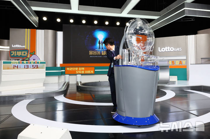 [서울=뉴시스] 황준선 기자 = 29일 오후 서울 마포구 MBC 경영센터 내 스튜디오에서 관계자들이 대국민 로또 6/45 추첨 공개방송 '645 데이'를 위해 추첨 장비를 옮기고 있다. 로또복권 추첨 과정의 공정성과 투명성을 알리기 위해 기획재정부 복권위원회 동행복권이 초청한 참관인 100명은 이날 추첨기 점검과 리허설, 추첨 생방송 등 추첨 절차의 전 과정을 참관한다. 2025.11.29. hwang@newsis.com