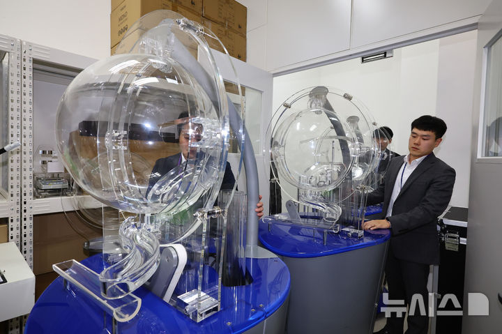 [서울=뉴시스] 황준선 기자 = 29일 오후 서울 마포구 MBC 경영센터 내 스튜디오에서 관계자들이 대국민 로또 6/45 추첨 공개방송 '645 데이'를 위해 추첨 장비를 옮기고 있다. 로또복권 추첨 과정의 공정성과 투명성을 알리기 위해 기획재정부 복권위원회 동행복권이 초청한 참관인 100명은 이날 추첨기 점검과 리허설, 추첨 생방송 등 추첨 절차의 전 과정을 참관한다. 2025.11.29. hwang@newsis.com