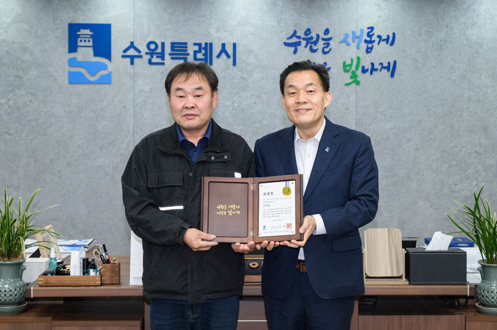 [수원=뉴시스] 이재준(오른쪽) 수원시장이 1일 시장 집무실에서 지난달 6일 매탄동 어린이보호구역 사고현장에서 차에 깔린 초등학생 구조에 앞장선 택시기사 조화용 씨에게 모범시민 표창을 수여하고 있다. (사진=수원시 제공) 2025.12.02. photo@newsis.com *재판매 및 DB 금지