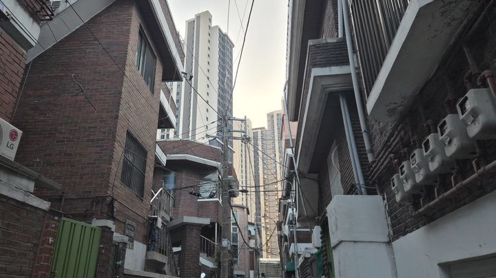 [서울=뉴시스] 정진형 기자 = 서울 광진구 자양동 자양1-4구역 가로주택정비사업 대상지의 골목 사이로 자양1구역 재건축으로 조성된 '롯데캐슬 리버파크 시그니처'가 보이고 있다. 2025.12.01. formation@newsis.com *재판매 및 DB 금지