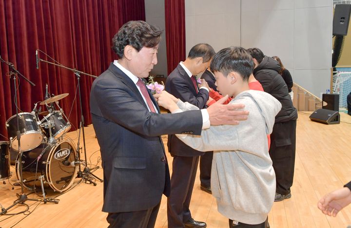 [횡성=뉴시스] 아동이 김군수 가슴에 꽃을 달아 주고 있다. (사진=횡성군 제공)2025.12.03.photo@newsis.com *재판매 및 DB 금지
