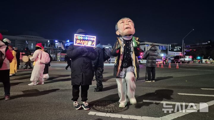 [서울=뉴시스] 전상우 수습기자 = 3일 오후 서울 여의도 국회의사당 인근에서 열린 '내란청산·사회대개혁 시민대행진'에서 한 참가자가 윤석열 전 대통령을 풍자한 대형 탈을 쓰고 춤을 추고 있다. 옆 참가자는 '내란수괴 윤석열을 심판하라'는 LED 피켓을 들고 있다. 2025.12.03. swoo@newsis.com 