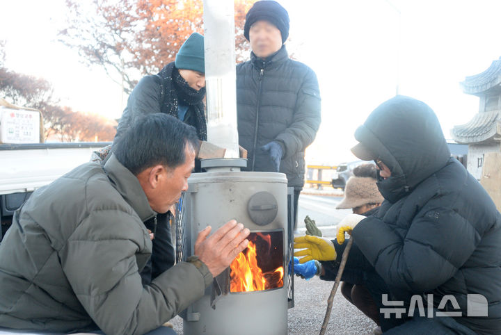 [전주=뉴시스] 김얼 기자 = 전북 전주시의 최저기온이 영하 4도를 기록하며 본격적인 겨울 날씨가 찾아온 3일 전주남부시장을 찾은 시민들이 화목난로를 쬐며 추위를 녹이고 있다. 2025.12.03. pmkeul@newsis.com