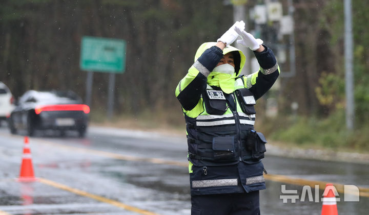 [제주=뉴시스] 우장호 기자 = 제주 산간에 대설특보가 내려진 3일 오전 제주시 1100도로 초입부인 어승생 삼거리에서 제주서부경찰서 소속 경찰관이 운전자들에게 교통 통제 수신호를 보내고 있다. 2025.12.03. woo1223@newsis.com
