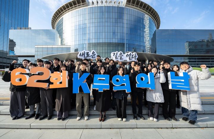 [서울=뉴시스] 3일 서울 강남구 코엑스 광장에서 한국무역협회 직원들이 무역의 날(12월 5일) 62주년을 앞두고 올해 슬로건인 'K-무역, 새로운 길을 열다'를 들고 기념촬영을 하고 있다. (사진=한국무역협회 제공) 2025.12.03. photo@newsis.com *재판매 및 DB 금지