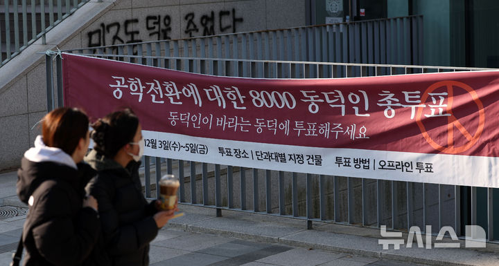[서울=뉴시스] 홍효식 기자 = 동덕여자대학교 공학 전환 타당성에 대한 외부 용역 결과 발표와 '공학 전환에 대한 8000 동덕인 의견 조사' 학생 총투표가 실시되는 3일 서울 성북구 동덕여대에서 학생들이 총투표 관련 현수막 앞을 지나가고 있다. 2025.12.03. yesphoto@newsis.com