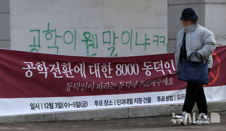 [서울=뉴시스] 홍효식 기자 = 동덕여자대학교 공학 전환 타당성에 대한 외부 용역 결과 발표와 '공학 전환에 대한 8000 동덕인 의견 조사' 학생 총투표가 실시되는 3일 서울 성북구 동덕여대에서 한 학생이 총투표 관련 현수막 앞을 지나가고 있다. 2025.12.03. yesphoto@newsis.com