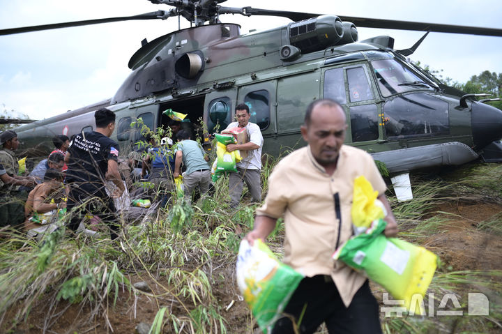 [AP/뉴시스] 6일 인도네시아  수마트라섬 북부 아체주에서 홍수 이재민들이 공군 헬리콥터가 실어온 구호식량을 받아가고 있다