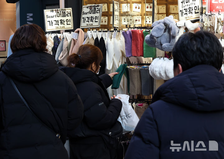 [서울=뉴시스] 최진석 기자 = 갑작스러운 강추위로 한파가 이어지고 있는 7일 서울 중구 명동에 한 상점에서 고객이 머플러와 장갑, 귀마개 등 방한용품을 고르고 있다. 2025.12.07. myjs@newsis.com