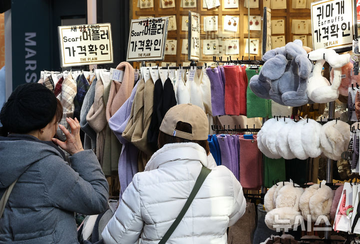 [서울=뉴시스] 최진석 기자 = 갑작스러운 강추위로 한파가 이어지고 있는 7일 서울 중구 명동에 한 상점에서 고객이 머플러와 장갑, 귀마개 등 방한용품을 고르고 있다. 2025.12.07. myjs@newsis.com