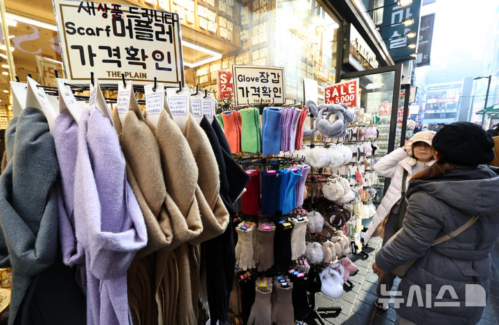 [서울=뉴시스] 최진석 기자 = 갑작스러운 강추위로 한파가 이어지고 있는 7일 서울 중구 명동에 한 상점에서 고객이 머플러와 장갑, 귀마개 등 방한용품을 고르고 있다. 2025.12.07. myjs@newsis.com