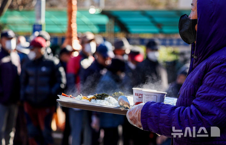 [대구=뉴시스] 이무열 기자 = 쌀쌀한 날씨를 보인 9일 대구 달서구 두류공원 사랑해밥차 무료 급식소에서 한 어르신이 배식 받은 점심을 들고 이동하고 있다. 2025.12.09. lmy@newsis.com