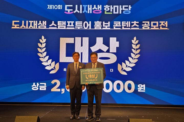 [밀양=뉴시스] 제10회 도시재생 한마당 행사에서 민병술(오른쪽) 밀양시도시재생지원센터 센터장이 도시재생 스탬프투어 홍보 콘텐츠 공모전 분야 대상을 수상하고 있다. (사진=밀양시 제공) 2025.12.11. photo@newsis.com *재판매 및 DB 금지