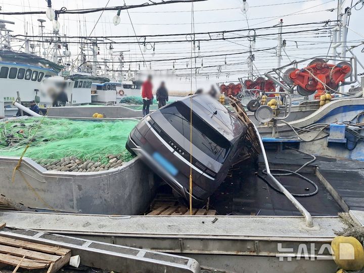 [제주=뉴시스] 11일 오후 2시50분께 제주시 한림읍의 한 도로에서 전기차량이 돌진해 정박 어선 위에 올라타 있다. (사진=제주소방안전본부 제공) 2025.12.11. photo@newsis.com
