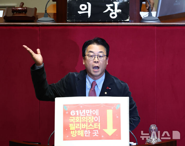 [서울=뉴시스] 김명년 기자 = 곽규택 국민의힘 의원이 11일 오후 서울 여의도 국회 본회의에서 형사소송봅 일부개정법률안에 대한 필리버스터(무제한 토론)를 하고 있다. 곽 의원은 지난번 본회의에서 벌어진 나경원 의원 토론 중단사태에 대해 항의하는 내용이 적힌 손피켓을 들고 토론에 나섰다. 2025.12.11. kmn@newsis.com