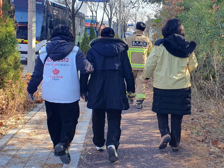 [광주=뉴시스] 이현행 기자 = 12일 낮 광주 서구 광주대표도서관 붕괴 현장에서 매몰된 작업자 가족이 재난심리회복 지원 인력의 부축을 받으며 걷고 있다. 2025.12.12. lhh@newsis.com *재판매 및 DB 금지