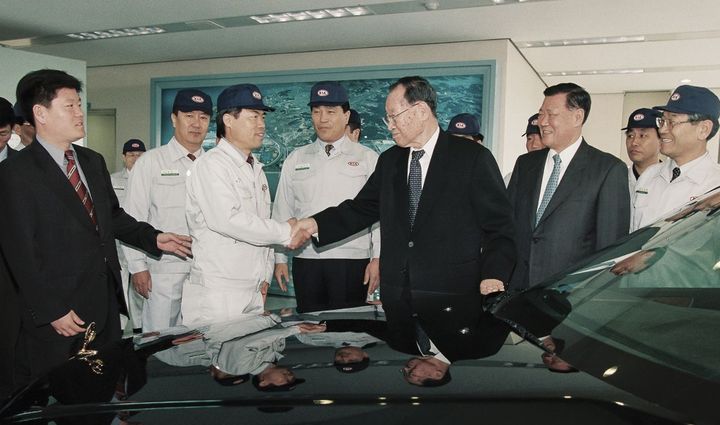 [서울=뉴시스] 정주영 현대차 창업회장과 정몽구 명예회장이 1999년 3월 기아 화성공장을 방문해 직원들을 격려하고 있다. (사진=기아 80년 사사) 2025.12.13. photo@newsis.com *재판매 및 DB 금지