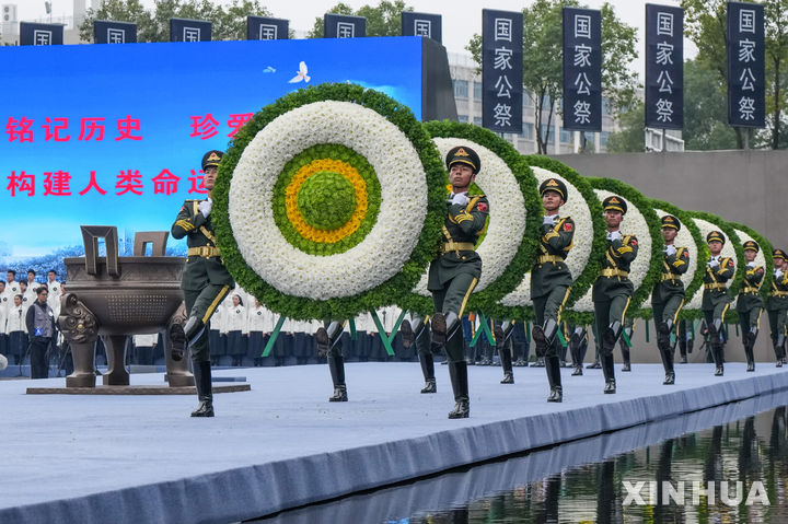  [난징=신화/뉴시스] 13일 장쑤성 난징의  ‘난징대도살 희생동포 기념관’에서 열린 난징대학살 기념식에서 인민해방군 군악대의 ‘국가 추모가’ 연주에 맞춰 인민해방군 의장대 16명이 여덟 개의 화환을 들고 추모 제단에 헌화하고 있다. 2025.12.13. 