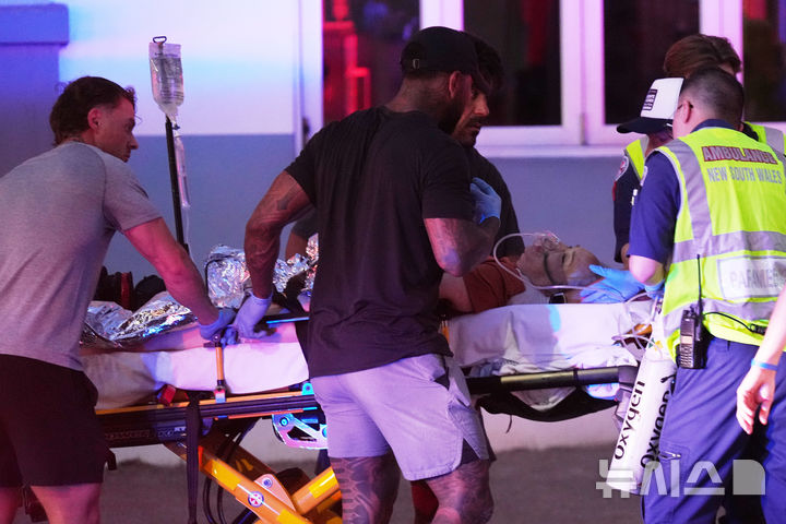 [시드니=AP/뉴시스] 14일(현지 시간) 호주 시드니 본다이 해변에서 열린 하누카(유대교 명절) 기념 행사에서 총격 사건이 발생해 구조대원들이 부상자를 이송하고 있다. 이날 남성 2명이 총기를 난사했으며 이 공격으로 16명이 숨지고 40명이 병원으로 이송됐다. 2025.12.15.