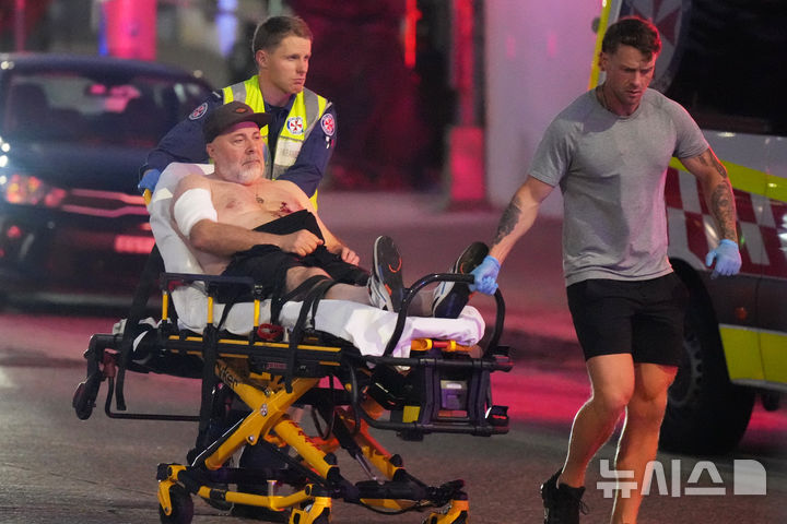 [시드니=AP/뉴시스] 14일(현지 시간) 호주 시드니 본다이 해변에서 열린 하누카(유대교 명절) 기념 행사에서 총격 사건이 발생해 구조대원들이 부상자를 이송하고 있다. 이날 남성 2명이 총기를 난사했으며 이 공격으로 16명이 숨지고 40명이 병원으로 이송됐다. 2025.12.15.