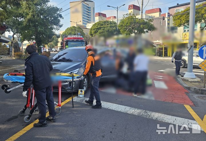 [제주=뉴시스] 15일 오후 제주시 이도동 소재 도로에서 휠체어 이용자가 승용차에 치여 소방당구이 구조에 나서고 있다. (사진=제주소방안전본부 제공) 2025.12.15. photo@newsis.com